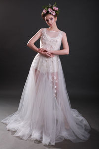 Portrait of young woman in wedding dress standing against black background