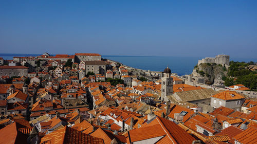 Aerial view of townscape by sea against clear sky