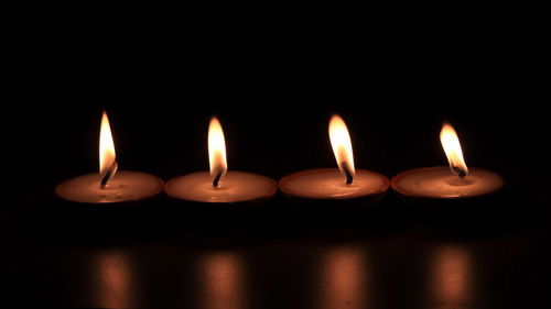 Close-up of burning candles against black background