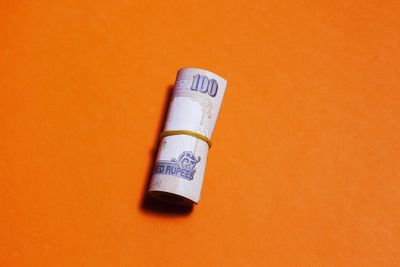 Close-up of paper currency on orange table