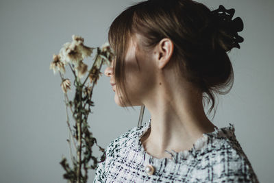 Close-up portrait of young woman against gray background