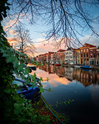 Canal amidst buildings in city against sky at sunset