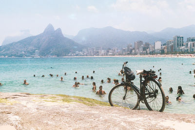 Bicycles on beach by city against sky