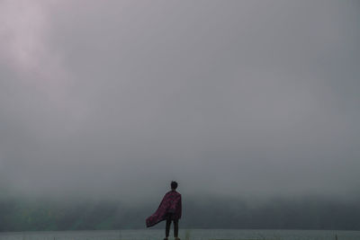 Rear view of man standing on street against sky