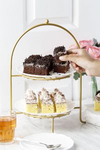 Female hand take chocolate cake from a high tea rier cake, concept english afternoon tea 