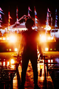 Full length of man holding drink while standing on pier at night