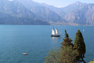 Sailboat sailing on sea against mountains