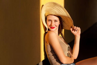 Portrait of beautiful young woman sitting in hat