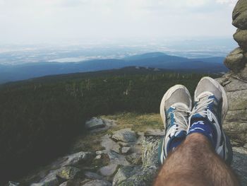 Low section of person on rock against sky