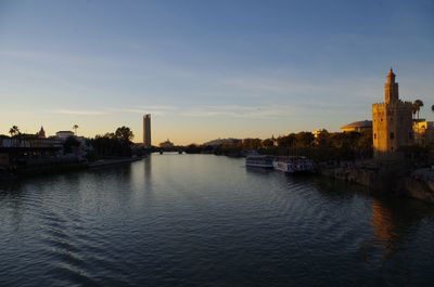 View of river and buildings against sky during sunset