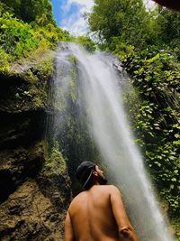 Rear view of man standing against waterfall