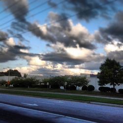 Cars on road against cloudy sky