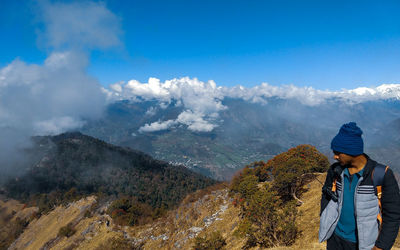 Man standing on mountain against blue sky