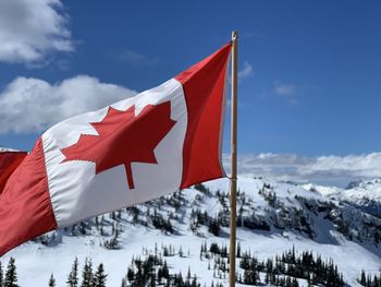 Flag of canada on snow covered mountain against sky in whistler 