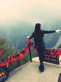 Young woman standing by love locks on railing at observation point against mountains