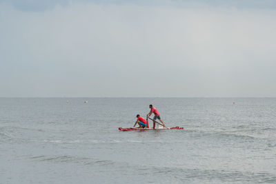 Men in boat on sea against sky