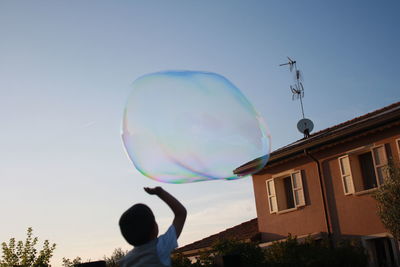 Low angle view of bubbles in mid-air against sky