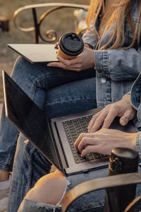 Close-up of hands of man and woman with laptop and tablet working , sitting on the bench in park