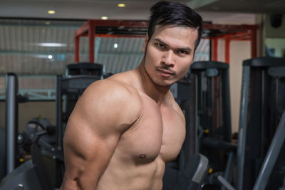 Portrait of shirtless muscular man flexing muscles in gym