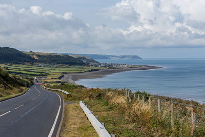 Scenic view of road by sea against sky