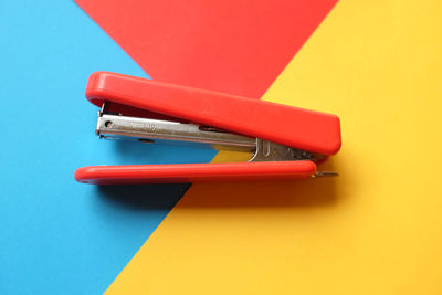 Flat lay a red hand stapler isolate on a colorful paper background