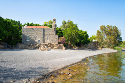 Old building by river against sky in city