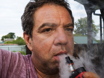 Close-up portrait of man smoking electronic cigarette