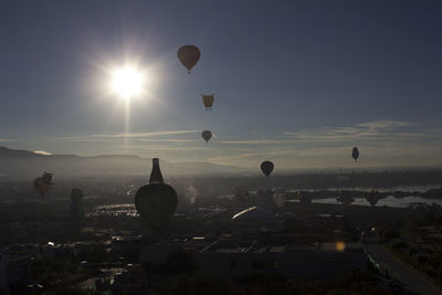 Hot air balloon flying over city against sky during sunset