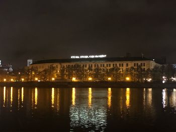 Illuminated buildings by river at night