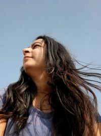 Portrait of a beautiful young woman looking away against sky