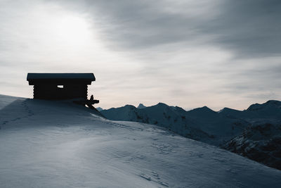 Lifeguard hut on snowcapped mountain against sky