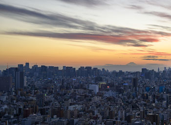 Sunset on tokyo cityscape with mount fuji in the back.