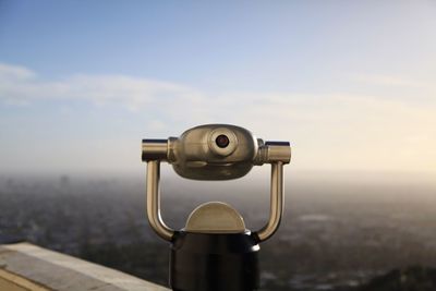 Close-up of coin-operated binoculars against cityscape