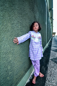 Portrait of cute girl standing against wall