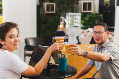 Happy couple hands holding glasses of beer toasting.