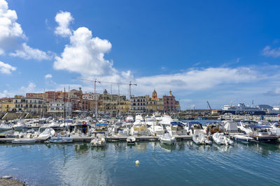 Sailboats moored in harbor against buildings in city