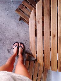 Low section of woman standing on floor by wooden table