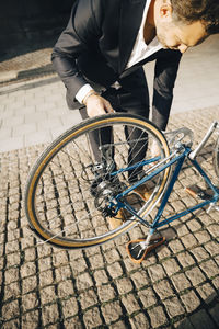 High angle view of businessman repairing bicycle on footpath in city