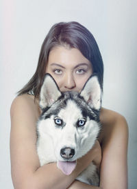Portrait of young woman with dog against white background