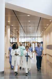 Male and female healthcare workers discussing while walking in hospital