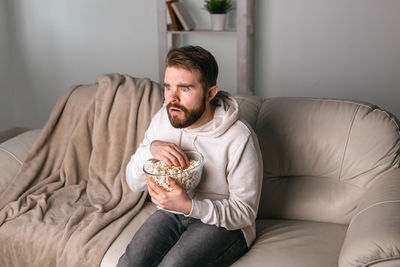 Full length of man sitting on sofa at home