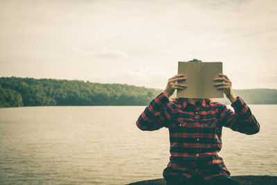 Man reading book while sitting outdoors