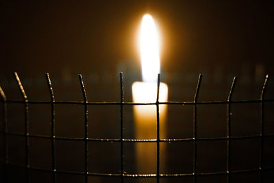 Close-up of illuminated candles on metal fence