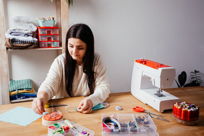 Young woman doing craft by table