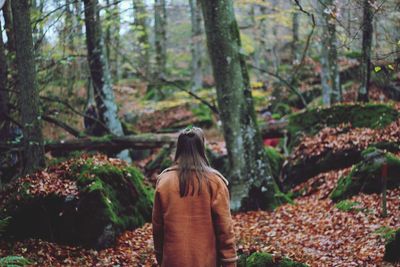 Rear view of woman standing in forest during autumn