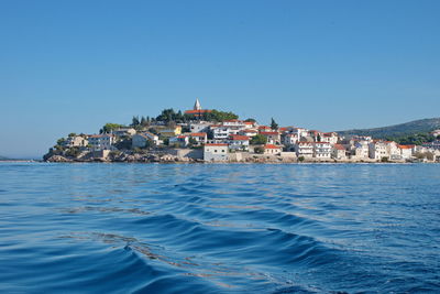 Sailing on motor boat on adriatic sea with primosten cityscape in the background.