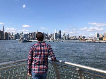 Rear view of man standing by railing against buildings