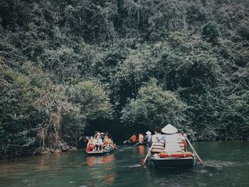 People on boat in river at forest