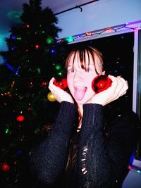 Portrait of young woman holding christmas tree