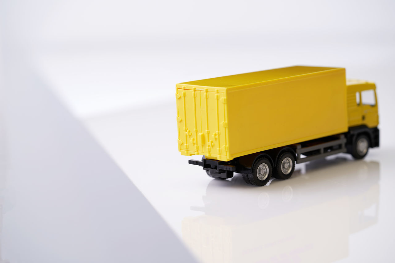 transportation, mode of transportation, motor vehicle, freight transportation, land vehicle, truck, business, vehicle, yellow, industry, container, car, distribution warehouse, shipping, delivering, copy space, warehouse, commercial land vehicle, box, indoors, wheel, toy, cargo container, no people